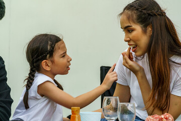 A half-breed child is pointing at something stuck in her mother's tooth.