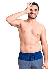 Fototapeta premium Young handsome man wearing swimwear smiling happy doing ok sign with hand on eye looking through fingers