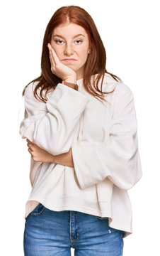 Young read head woman wearing casual sweatshirt thinking looking tired and bored with depression problems with crossed arms.