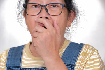 Facial expression of an Asian woman looking shocked with hand covering her mouth