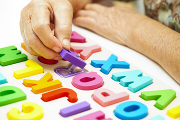 Asian elderly woman playing puzzles game for treatment dementia prevention and Alzheimer disease.