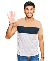 Young handsome man wearing casual clothes showing and pointing up with fingers number five while smiling confident and happy.