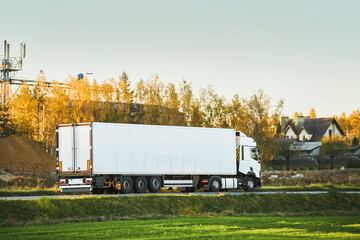 Commercial vehicles for shipping and post delivery drive on a motorway. White trucks with semi trailers carrying cargo containers. Sustainable and efficient logistics practices to transport goods.