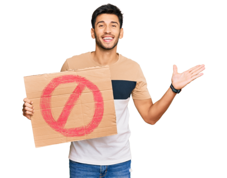 Young handsome man holding prohibited warning banner celebrating victory with happy smile and winner expression with raised hands