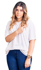Fototapeta premium Young caucasian woman wearing casual clothes pointing with hand finger to the side showing advertisement, serious and calm face
