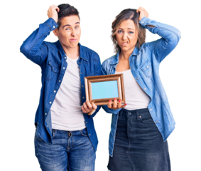 Couple of women holding empty frame confuse and wondering about question. uncertain with doubt, thinking with hand on head. pensive concept.