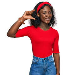 Beautiful african young woman wearing casual clothes smiling and confident gesturing with hand doing small size sign with fingers looking and the camera. measure concept.