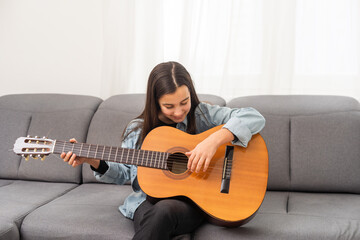 beautiful young girl plays guitar at home