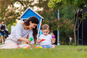 Mother and toddler boy playing in the park while having picnic