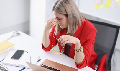 Tired woman at working table in office. Irregular working hours and deadlines concept