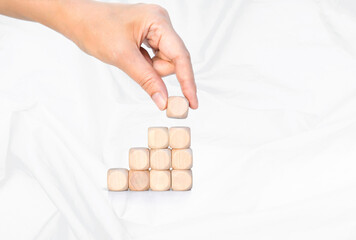 Wooden cube stack with hand holding wooden cube isolate on white background, building block to success