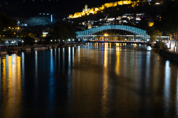 Panoramic landscape of downtown Tbilisi at night with church and bridge of peace