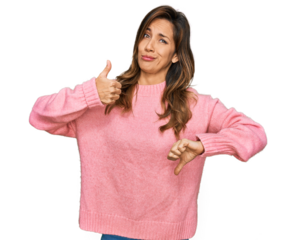 Young hispanic woman wearing casual clothes doing thumbs up and down, disagreement and agreement expression. crazy conflict