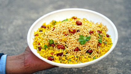 indian breakfast dish poha.Indian breakfast Poha topped with peanuts, pomegranate seeds, chopped...