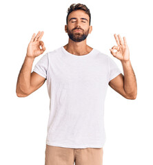 Young hispanic man wearing casual white tshirt relax and smiling with eyes closed doing meditation gesture with fingers. yoga concept.