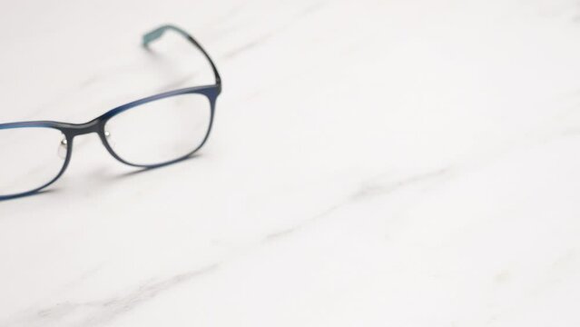 Close-up shot panning and revealing a pair of eyeglasses that is placed on a table.