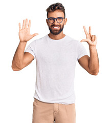 Young hispanic man wearing casual clothes and glasses showing and pointing up with fingers number eight while smiling confident and happy.