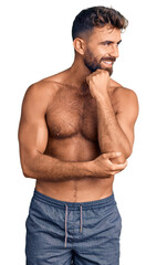 Fototapeta premium Young hispanic man wearing swimwear shirtless with hand on chin thinking about question, pensive expression. smiling with thoughtful face. doubt concept.