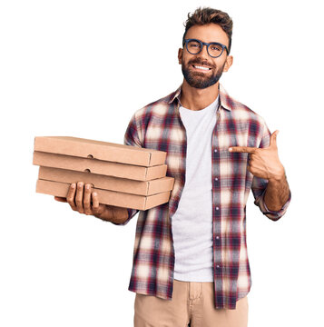 Young hispanic man holding delivery pizza box pointing finger to one self smiling happy and proud