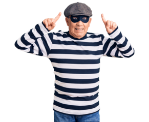 Senior handsome man wearing burglar mask and t-shirt smiling amazed and surprised and pointing up with fingers and raised arms.