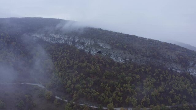 Approaching drone shot and panning above the Kozarnika Cave, located in the Balkan Mountain range, in Dimovo Municipality, in Bulgaria.