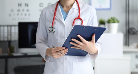 Woman doctor holding clipboard with documents in her hands closeup. Health insurance concept - obrazy, fototapety, plakaty