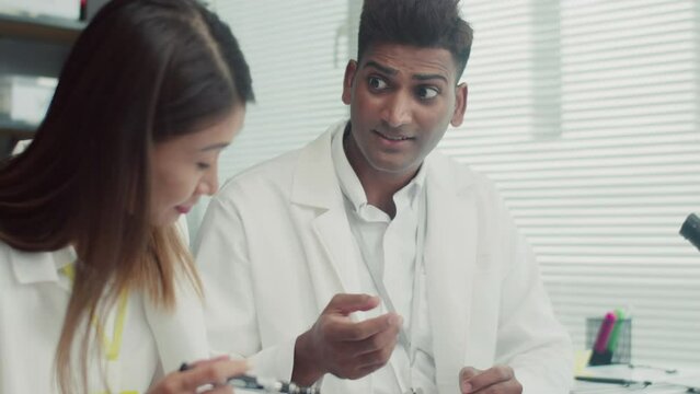 Handheld shot of two technicians in white coats using screwdriver when repairing broken component of mobile phone at service centerHandheld shot of two technicians in white coats using screwdriver whe