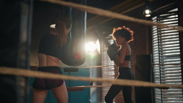 Two woman boxers boxing training. Coach sport trainer and young sportswoman in boxing gloves boxes and preparing to fight competition on boxing ring. Training, workout professional sport concept.
