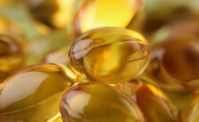 Golden transparent capsules in organic packaging. Unsaturated fatty acids concept