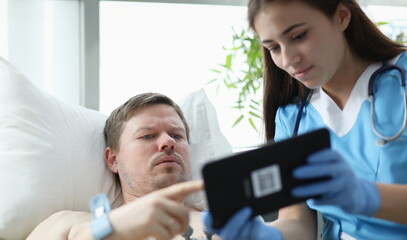 Fototapeta premium Doctor showing patient data on digital tablet in hospital. ECG diagnosis of heart disease concept