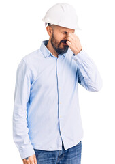 Young handsome man wearing architect hardhat tired rubbing nose and eyes feeling fatigue and headache. stress and frustration concept.