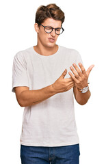 Handsome caucasian man wearing casual clothes and glasses suffering pain on hands and fingers, arthritis inflammation