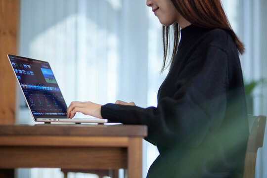 ノートパソコンにて動画編集を行うクリエイターの日本人女性