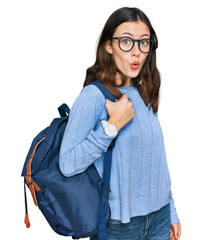 Young beautiful girl wearing student backpack scared and amazed with open mouth for surprise,...