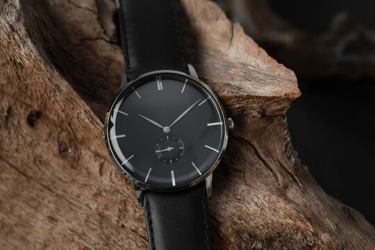 Close-up of men's wrist watch with a black leather strap on a wooden background. 