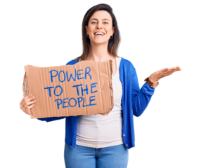 Young beautiful woman holding power to the people banner celebrating victory with happy smile and winner expression with raised hands
