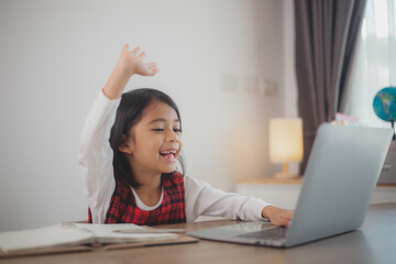 Cute and happy little Asian girl children using a laptop computer, studying through an online...