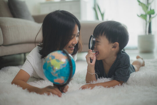 Asian little girls and boys are learning the globe model, the concept of save the world, and learning through play activities for kid education at home.