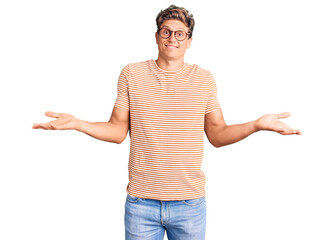 Young handsome man wearing casual clothes and glasses clueless and confused expression with arms...