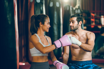 Vitality and smart young couple, friend or boxer and trainer helping to wearing a glove, Training and teaching boxing in gym or sport center, teamwork and cheering up, wellbeing exercising lifestyles.
