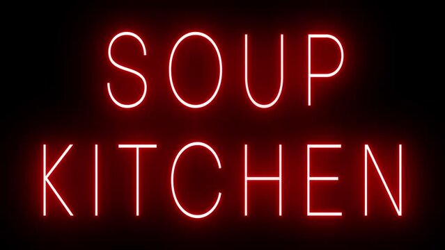 Flickering red retro style neon sign glowing against a black background for SOUP KITCHEN