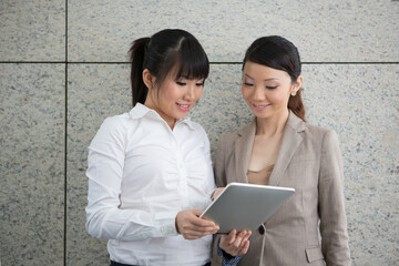  Two girls looking at a touch screen tablet.