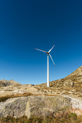 Fototapeta na wymiar Wind turbine on rocks against blue sky on the Gotthard Pass, Canton of Ticino, Switzerland