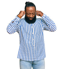 Fototapeta premium Young african american man wearing business shirt covering ears with fingers with annoyed expression for the noise of loud music. deaf concept.