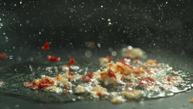 garlic and chili frying ingredients seasoning boiling in steel pan hot and spicy splash spring 4k slow motion