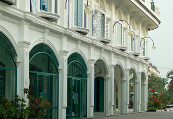 The outdoor architecture of a white, avant-garde style building is equipped with a green iron fence