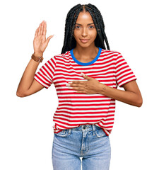 Beautiful hispanic woman wearing casual clothes swearing with hand on chest and open palm, making a...