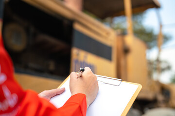 Action of an engineer hand is writing to perform inspection of the road roller or road compactor...