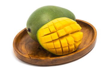Cut into cubes and whole fresh organic green mango delicious fruit side view in a wooden plate isolated on white background clipping path