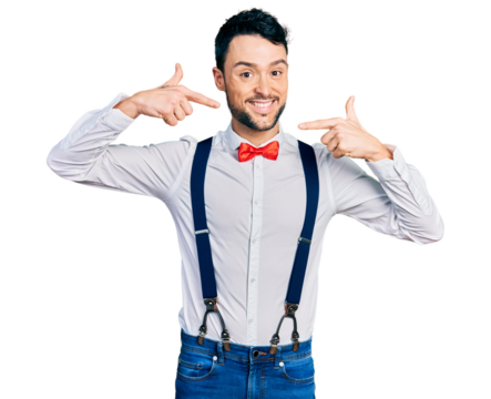 Hispanic man with beard wearing hipster look with bow tie and suspenders smiling cheerful showing and pointing with fingers teeth and mouth. dental health concept.
